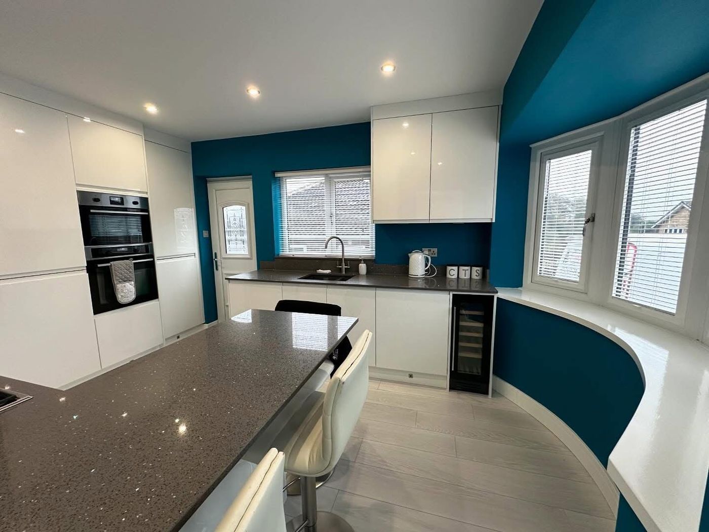 Finished kitchen with white units and a blue feature wall